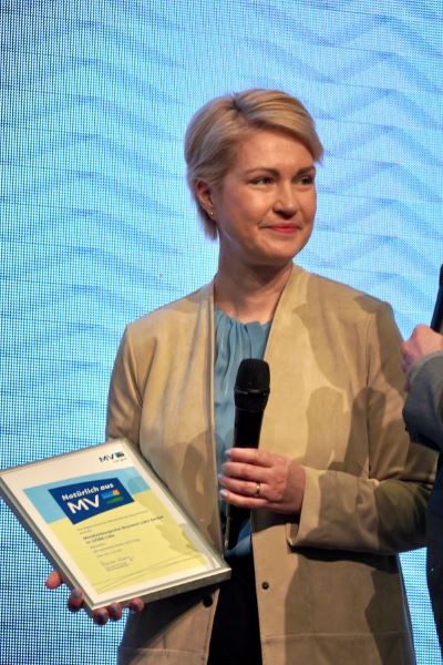 Ministerpräsidentin Manuela Schwesig mit Mikrophon und Urkunde mit dem neuen Regionalzeichen in den Händen